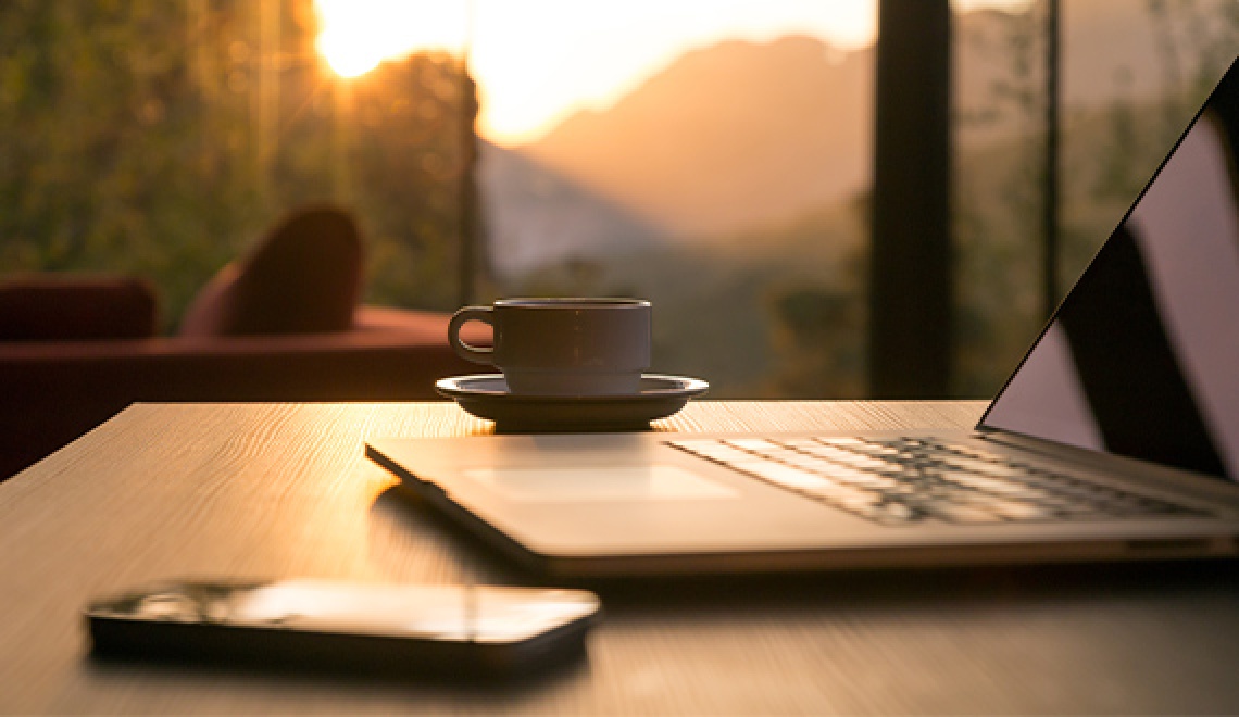 Laptop, Handy und Kaffee Tasse im Sonnenschein