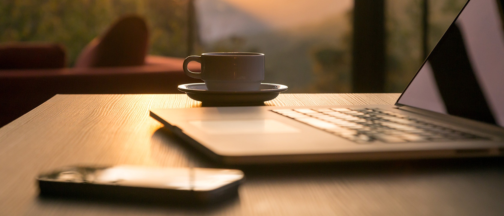 Laptop, Handy und Kaffee Tasse im Sonnenschein